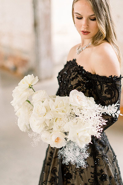 Detail shot of bouquet and black wedding dress