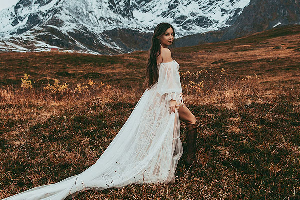 Caroline posing in her boho wedding dress in the mountains