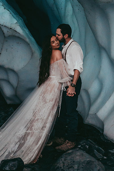 Caroline posing in her wedding dress in an ice cave