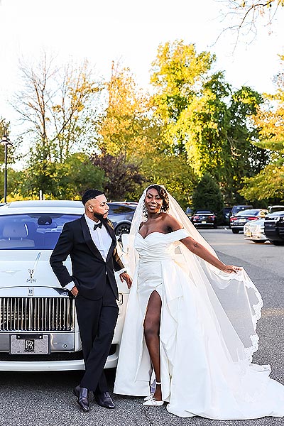 Jenneh and Darell posing in front of a car
