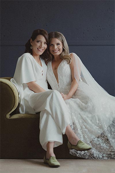 Susan and Madison posing on a couch in their bridal attire