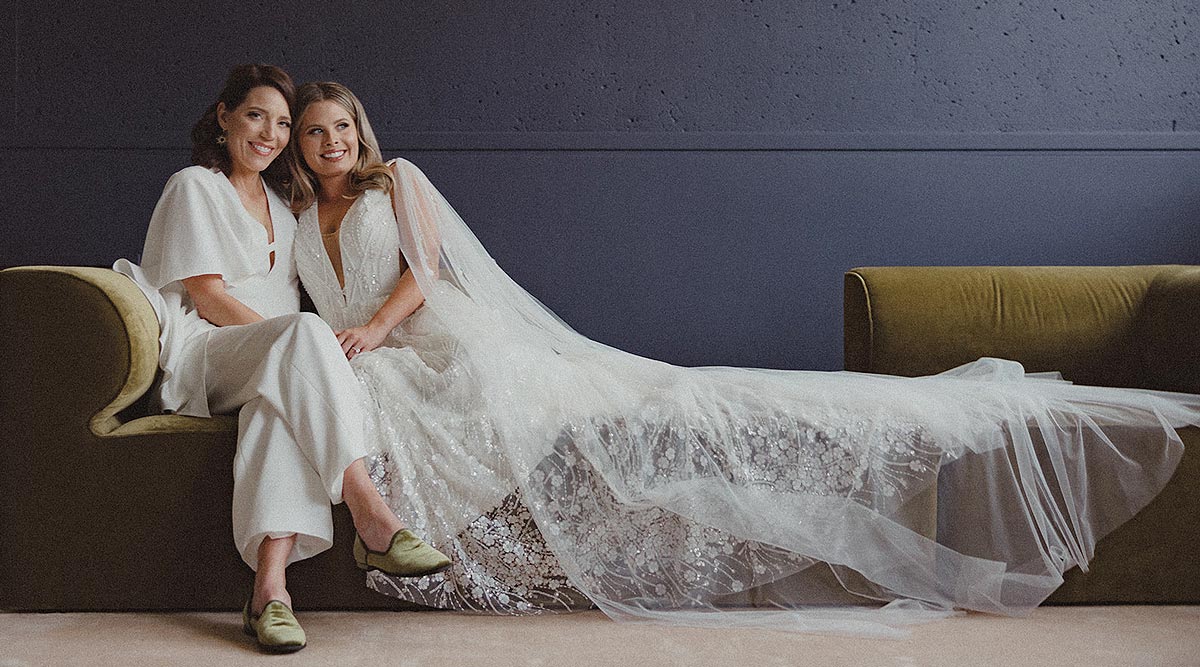 Susan and Madison posing on a couch in their custom wedding attire