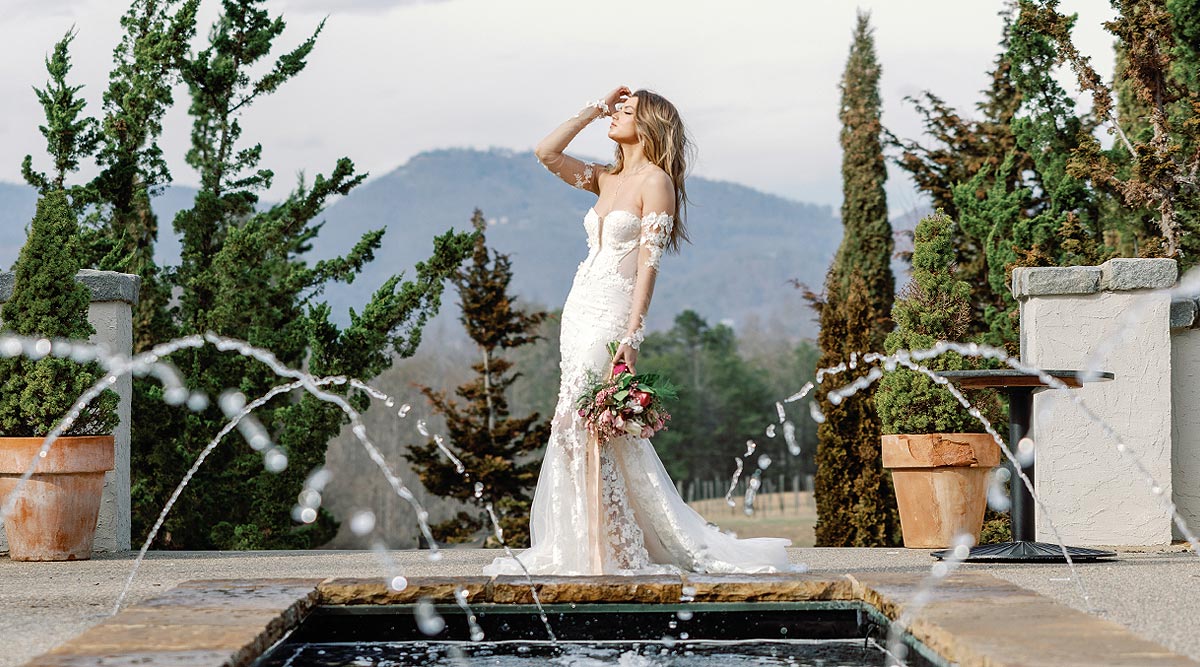 Kyra in her custom wedding dress posing in front of a fountain