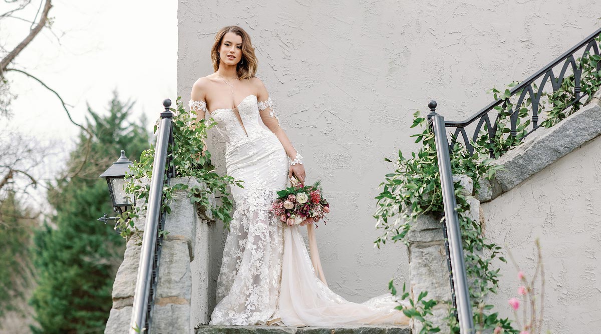 Kyra posing on a balcony in a romantic wedding dress