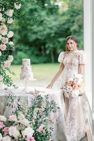 Masha posing with a wedding cake in her custom wedding gown