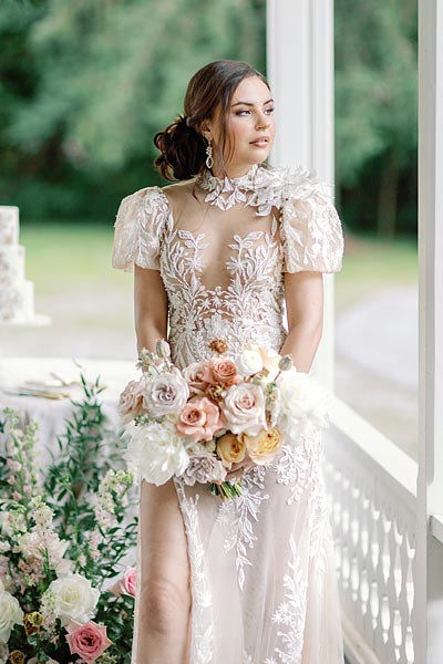 Masha posing on a porch with her wedding bouquet