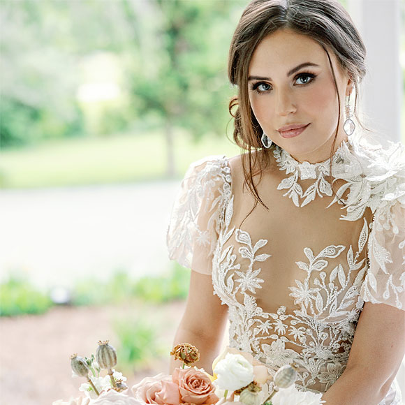 Masha posing with her bouquet in a custom wedding dress