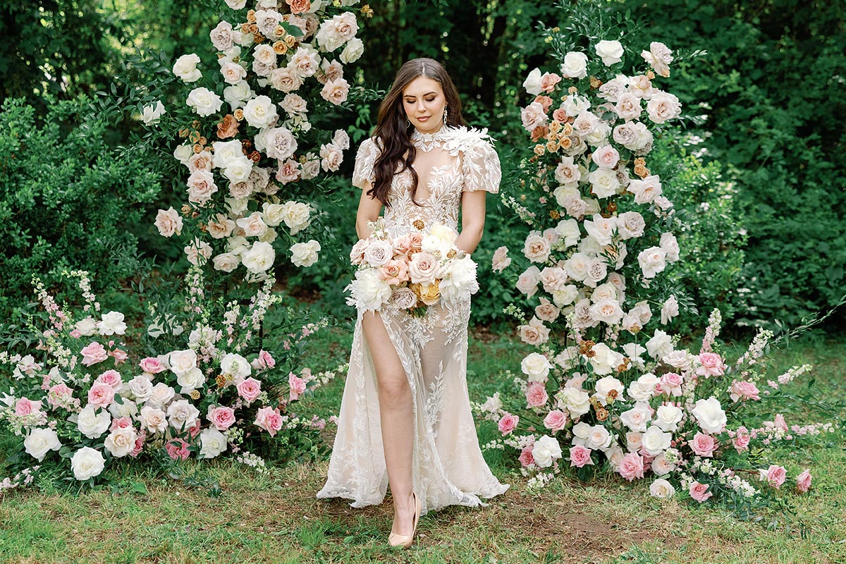 Masha posing in her custom wedding dress with a flower arrangement