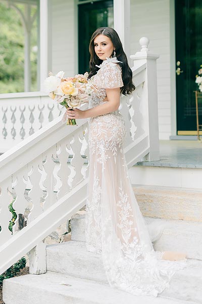 Masha posing with a bouquet in her custom wedding dress