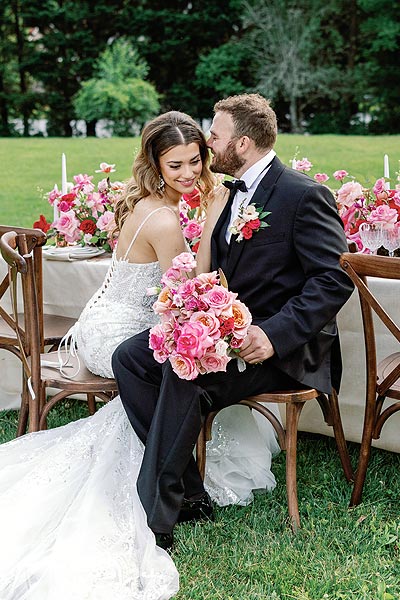 Kyra and will posing at their wedding reception table