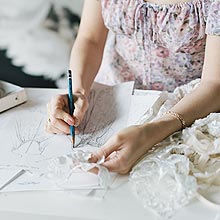 Angela's hands creating a custom wedding dress sketch.