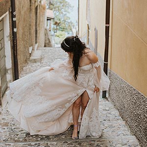 Morgan carrying her wedding dress train up an alley in Italy.