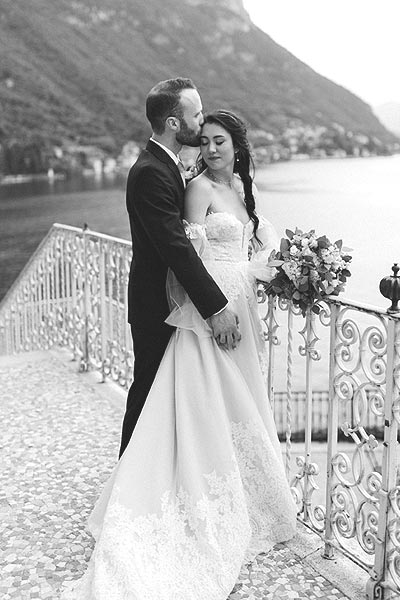 Morgan in her wedding gown posing with Alec on a veranda in Italy