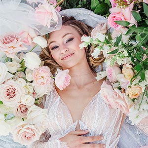 Natalie laying in a bed of flowers in her wedding dress.