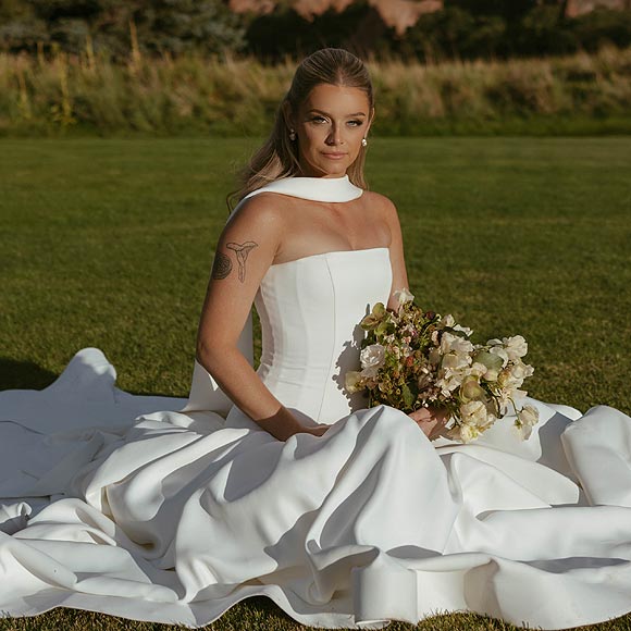 Hannah sitting and posing for a bridal portrait in her custom wedding dress.